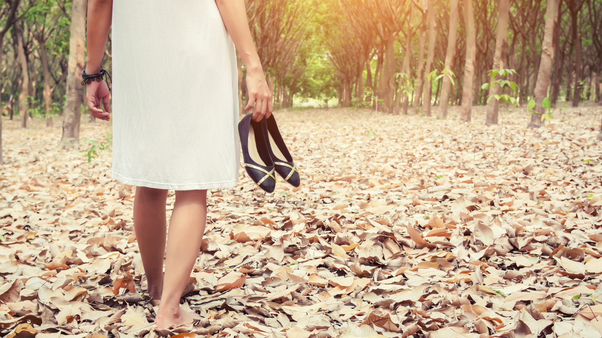 Mulher caminhando descalça em folhas secas na floresta